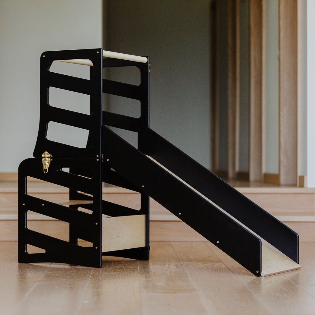 var:schwarz-lernturm-rutsche / var:schwarz-lernturm-rutsche-hocker / Der schwarze Lernturm mit Rutsche im Streifen-Design im Fokus.