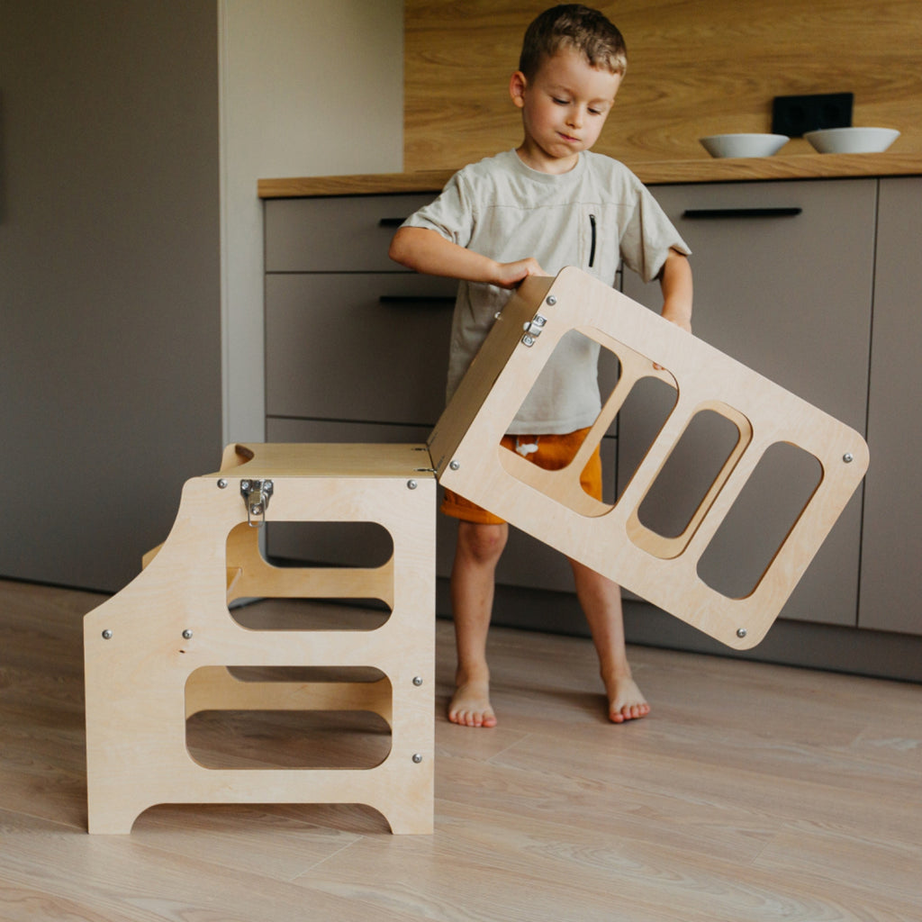 var:klarlack-lernturm / var:klarlack-lernturm-rutsche / var:klarlack-lernturm-hochstuhl / Ein Kind baut den 2in1 Lernturm in Klarlack zum Kindertisch um.