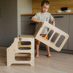 var:klarlack-lernturm / var:klarlack-lernturm-rutsche / var:klarlack-lernturm-hochstuhl / Ein Kind baut den 2in1 Lernturm in Klarlack zum Kindertisch um.