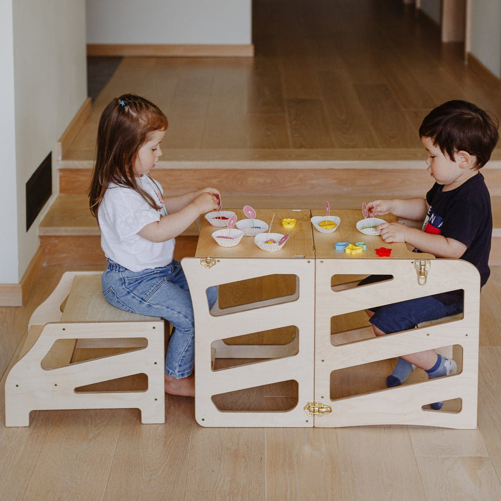var:klarlack-lernturm-hocker / var:klarlack-lernturm-rutsche-hocker / Zwei Kinder sitzen gemeinsam am zum Tisch umgebauten Lernturm iM Streifen-Design in der Variante Klarlack. Sie machen gemeinsam Muffins aus Knete.
