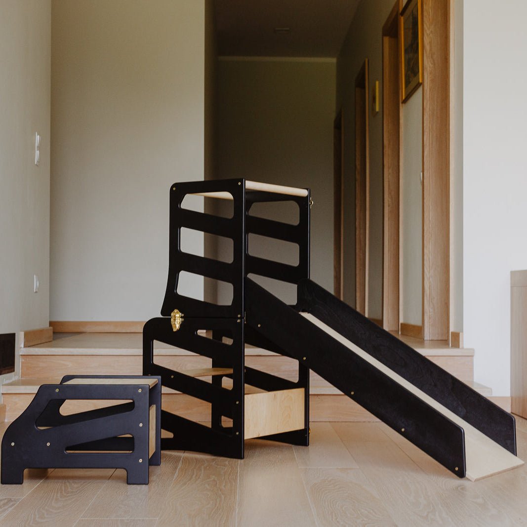 var:schwarz-lernturm-rutsche-hocker / Der schwarze 4in1 Lernturm im Streifen-Design im Fokus.