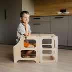 var:klarlack-lernturm / var:klarlack-lernturm-rutsche / var:klarlack-lernturm-hochstuhl / Lernturm in Klarlack (Naturholz) umgeklappt zum Kindertisch – integrierte Sitzbank für Mahlzeiten und zum spielen.