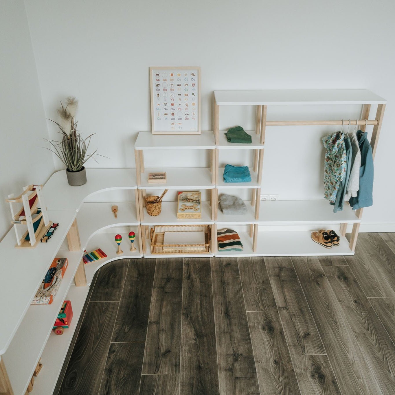 Der Kleiderschrank nach Montessori in Weiß mit weiteren modularen Kindermöbeln der MODURA Kollektion kombiniert als smarte Ecklösung zur Aufbewahrung im Kinderzimmer.