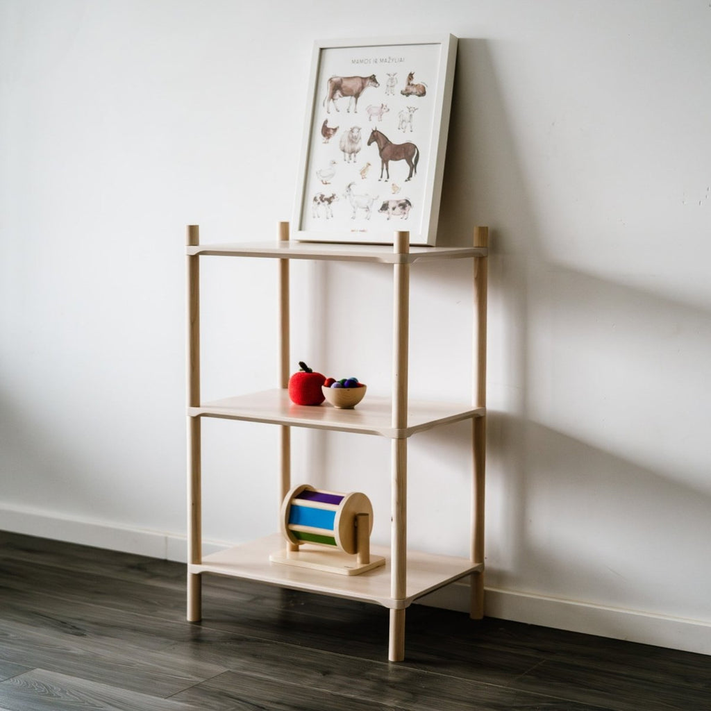 Das modulare Holzregal "Mini" für Kinder & Erwachsene mit drei Regalböden steht vor einer weißen Wand. Oben drauf steht ein Bild mit animierten Tiueren und in den darunter liegenden Fächern sind Holzspielsachen angeordnet