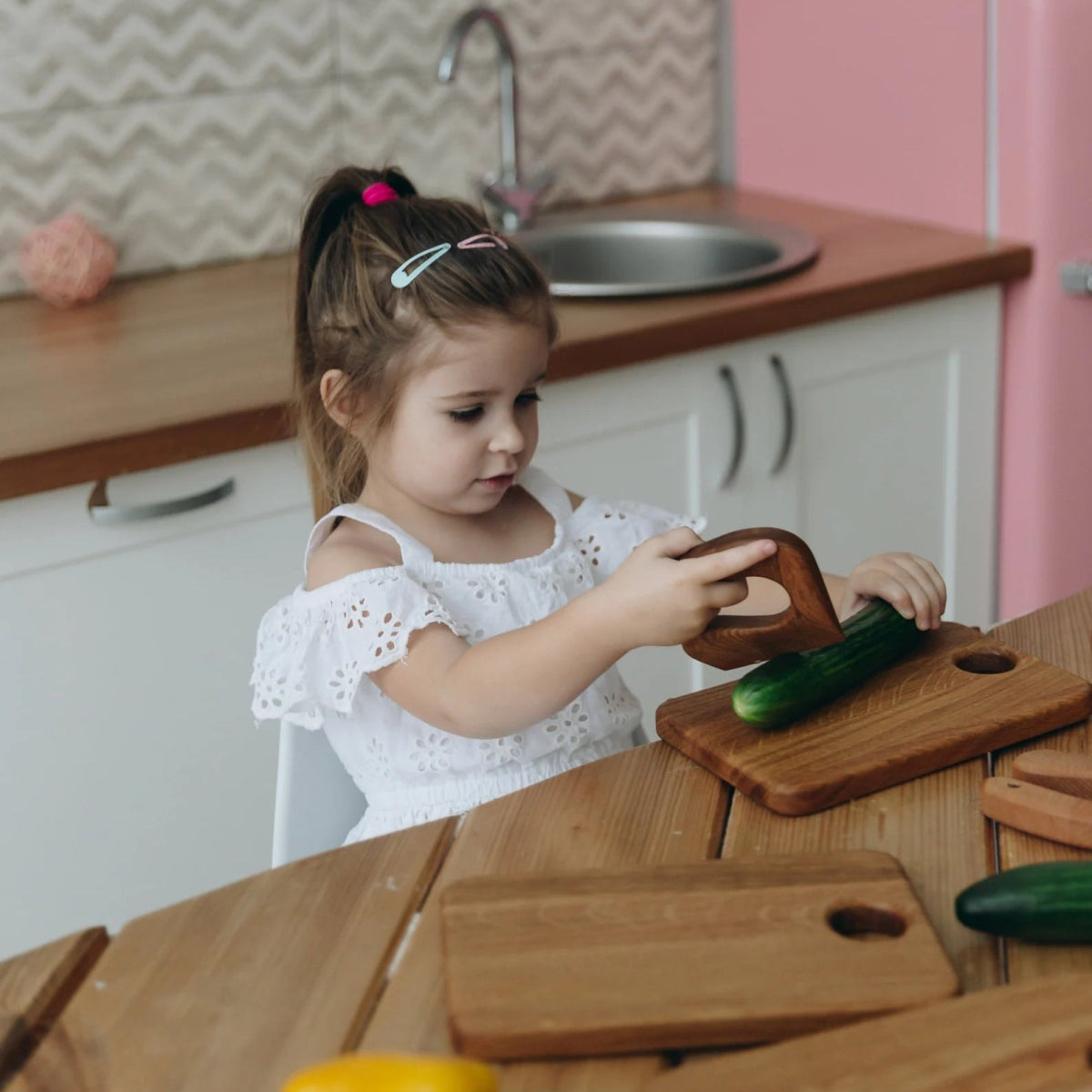 Ein Kind versucht mit einem Montessori Kindermesser eine Gurke zu schneiden.